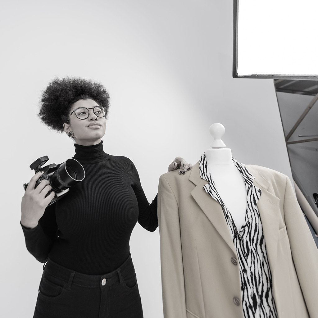 Donna fotografa ripresa in un momento di pausa durante uno shooting per digitalizzare e alimentare l'archivio digitale dell'azienda